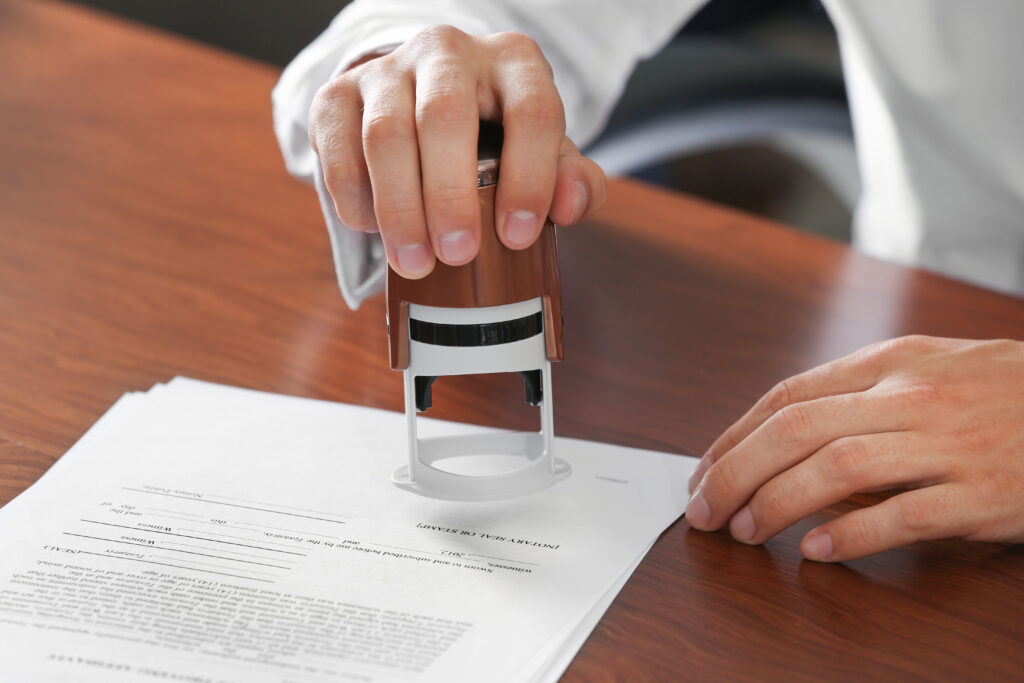 A notary applying an official stamp to legal documents on a desk